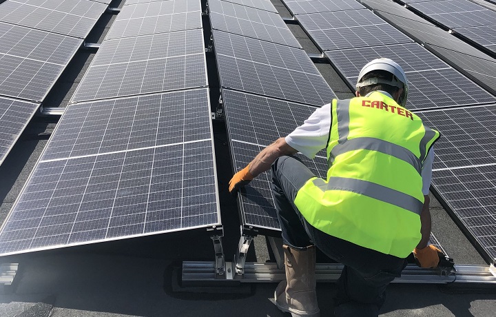 Construction worker fitting solar panels on a flat roof construction worker fitting solar panels on a flat roof
